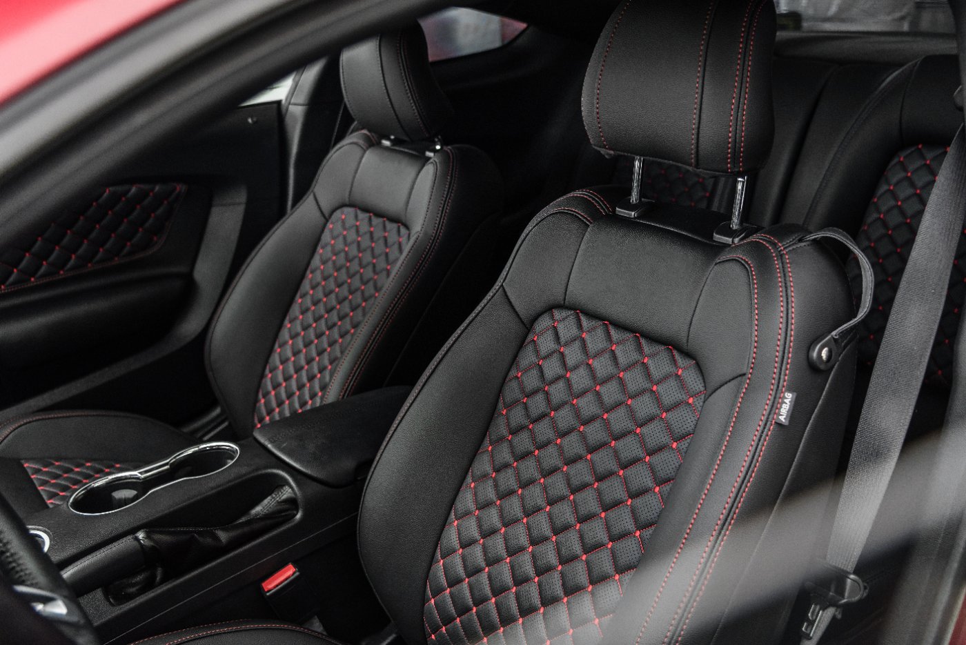 Premium black leather car seats with red quilted diamond stitching pattern and red accent threading in sports vehicle interior