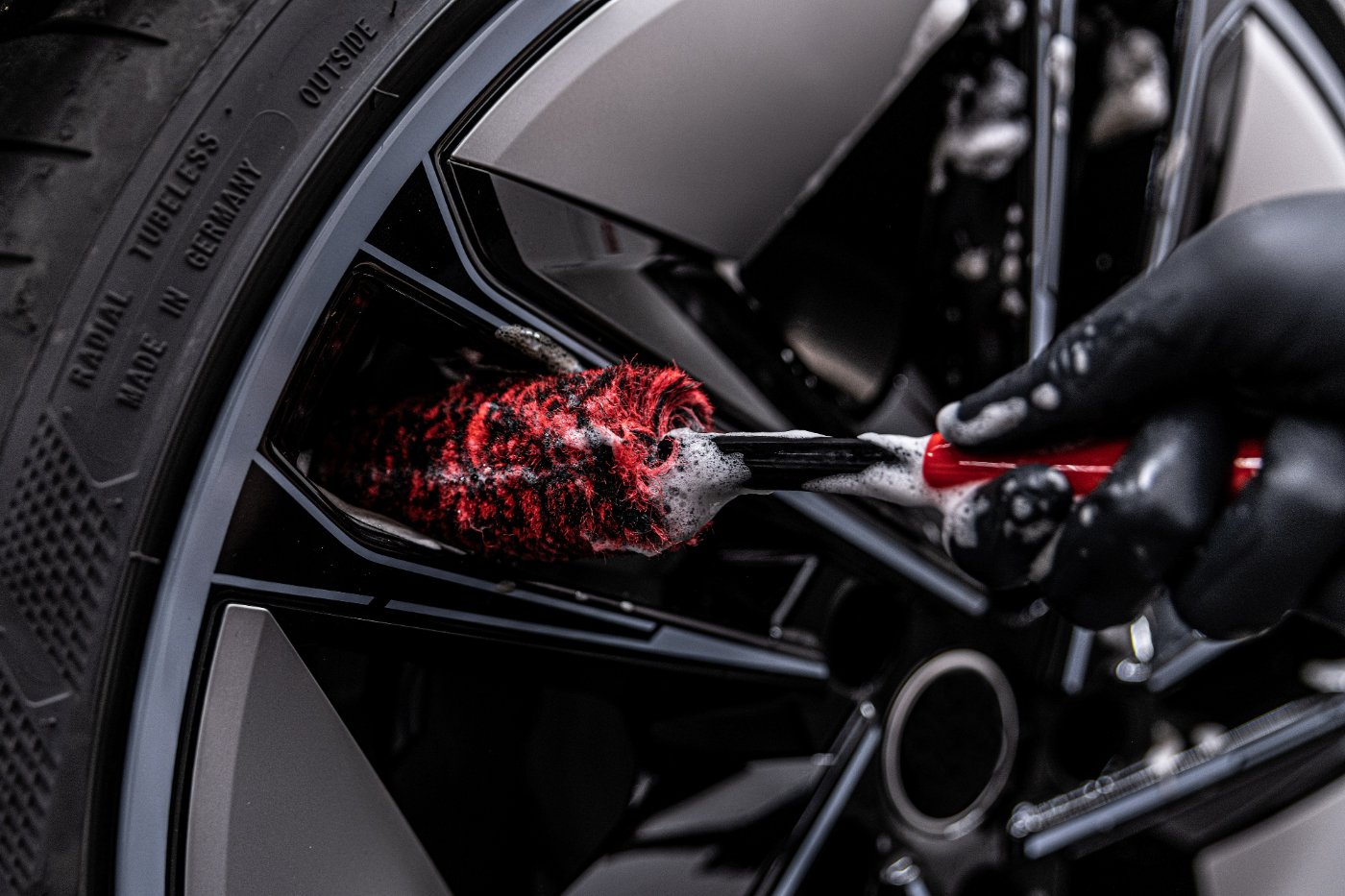 Red brush cleaning car wheel and tire during detailing service